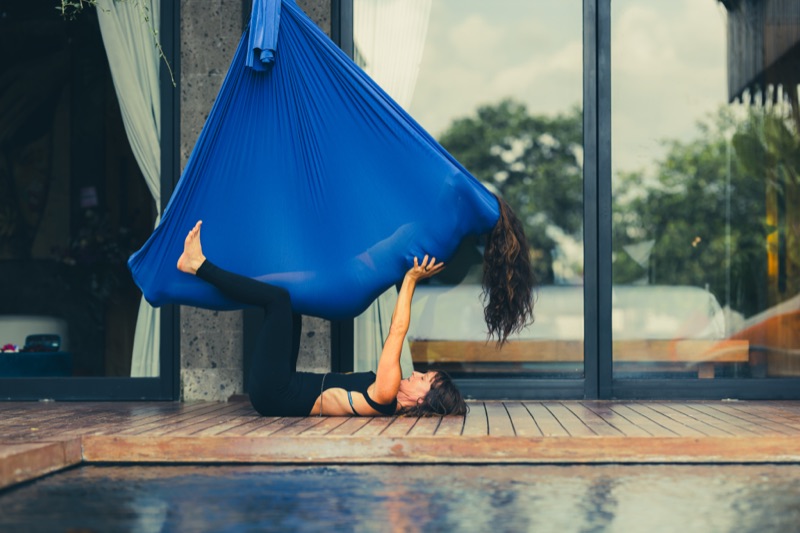 A client fully suspended and inverted in the blue Somatic Swing inside the Aum Dome