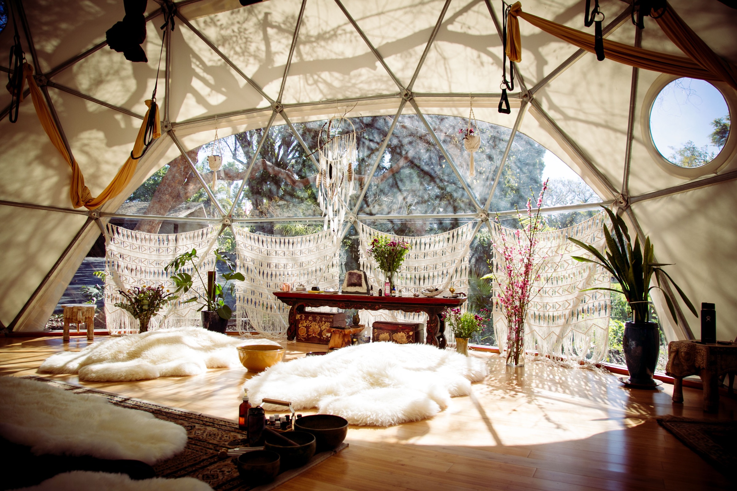 The sunlit interior of the Aum Dome with sheepskins, altar, and warm light