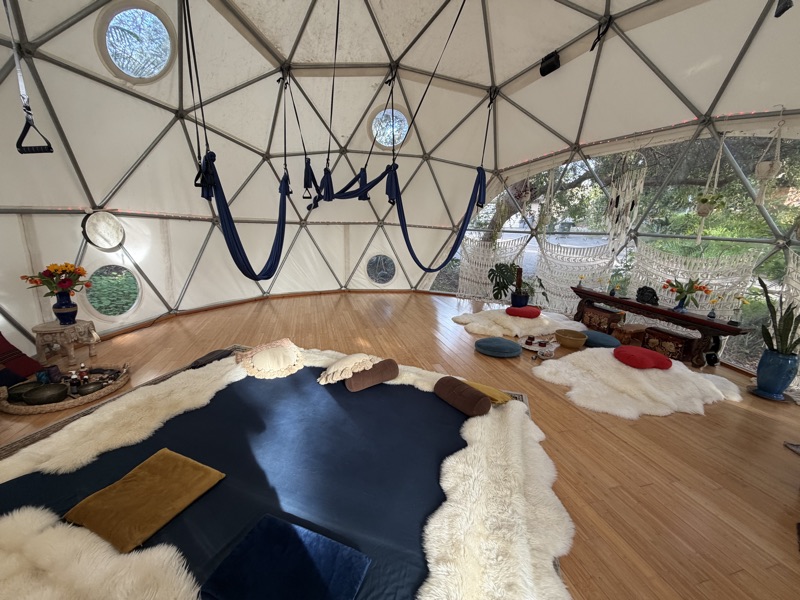Blue Somatic Swings hung above a navy mat on the floor of the Aum Dome