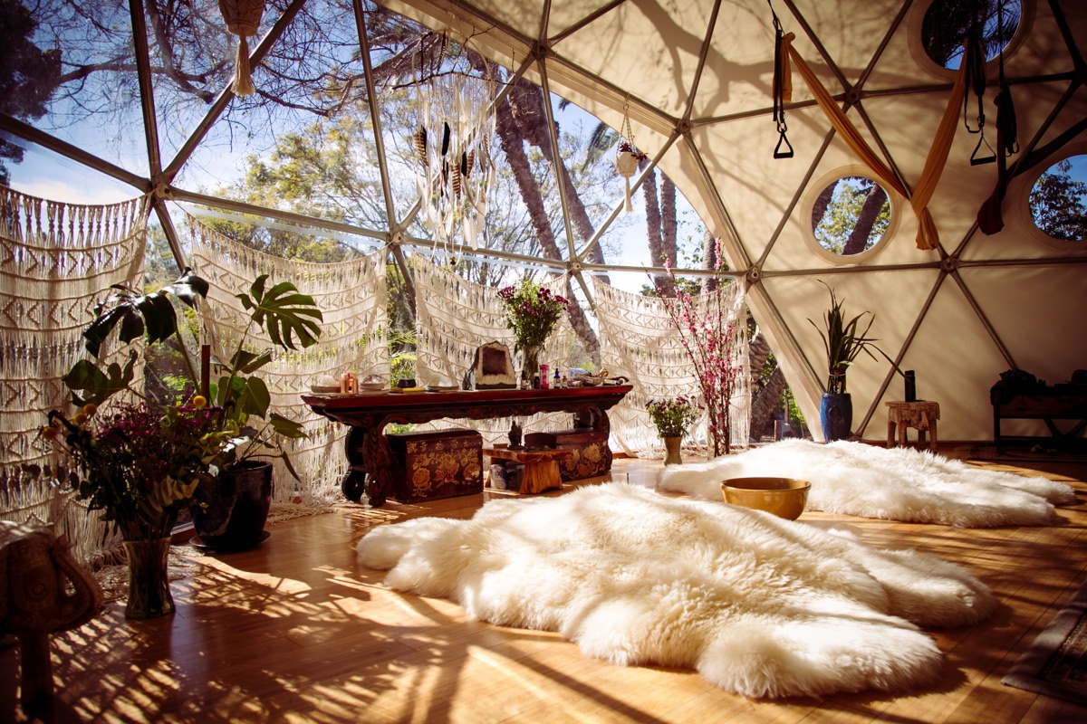 A wide view of the sunlit Aum Dome interior with sheepskins