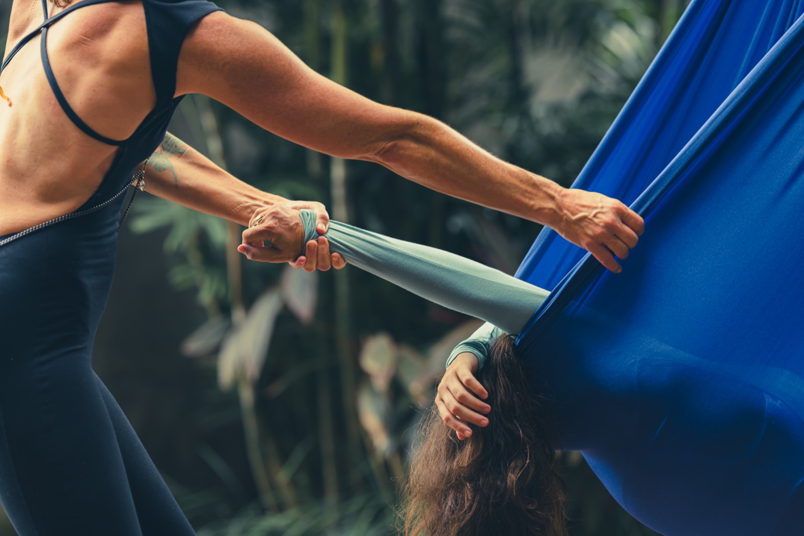 A close-up of hands adjusting the fabric of the Somatic Swing around a client