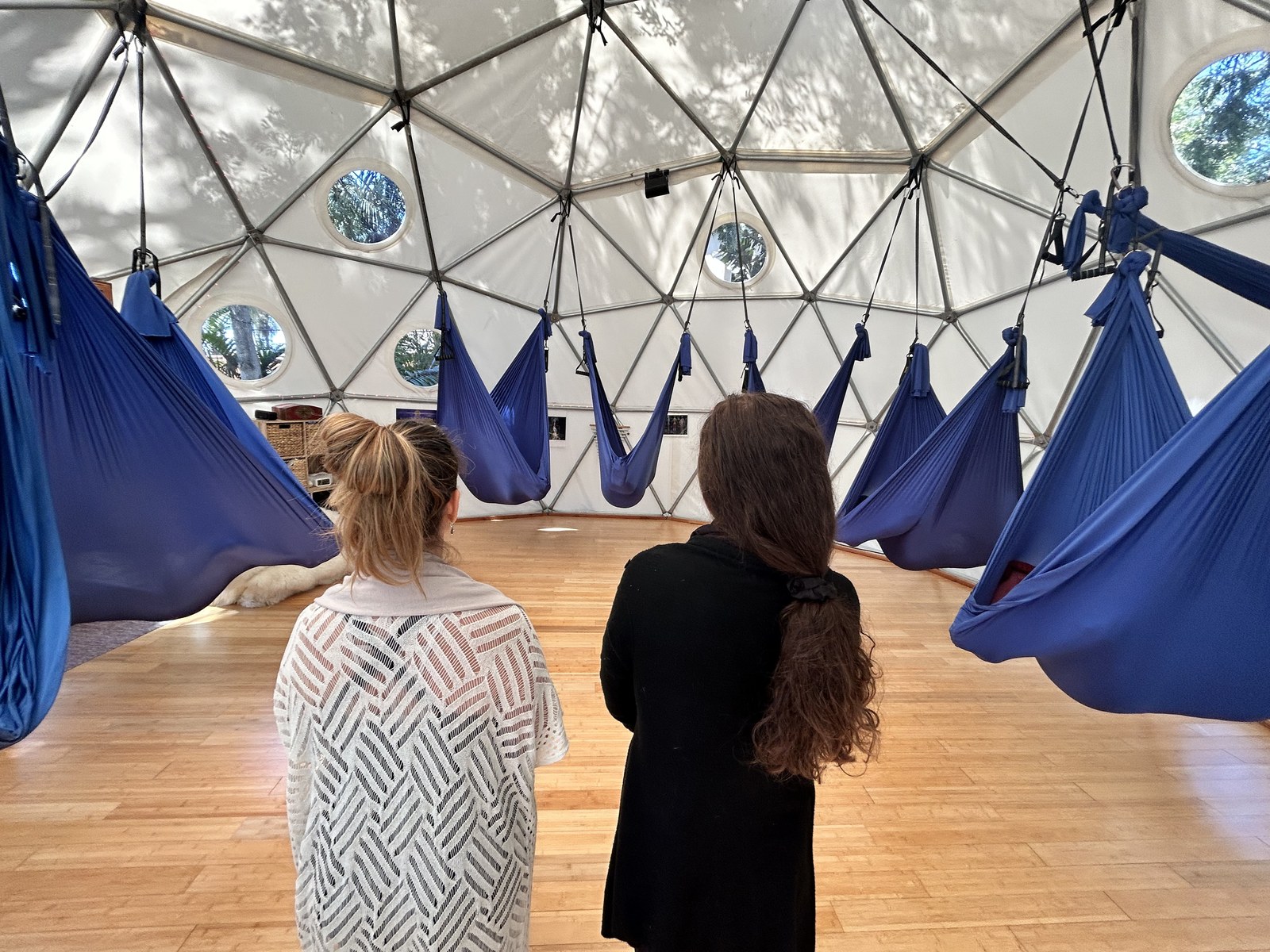 A person in the foreground looking across the Aum Dome at the ring of swings hanging around the room