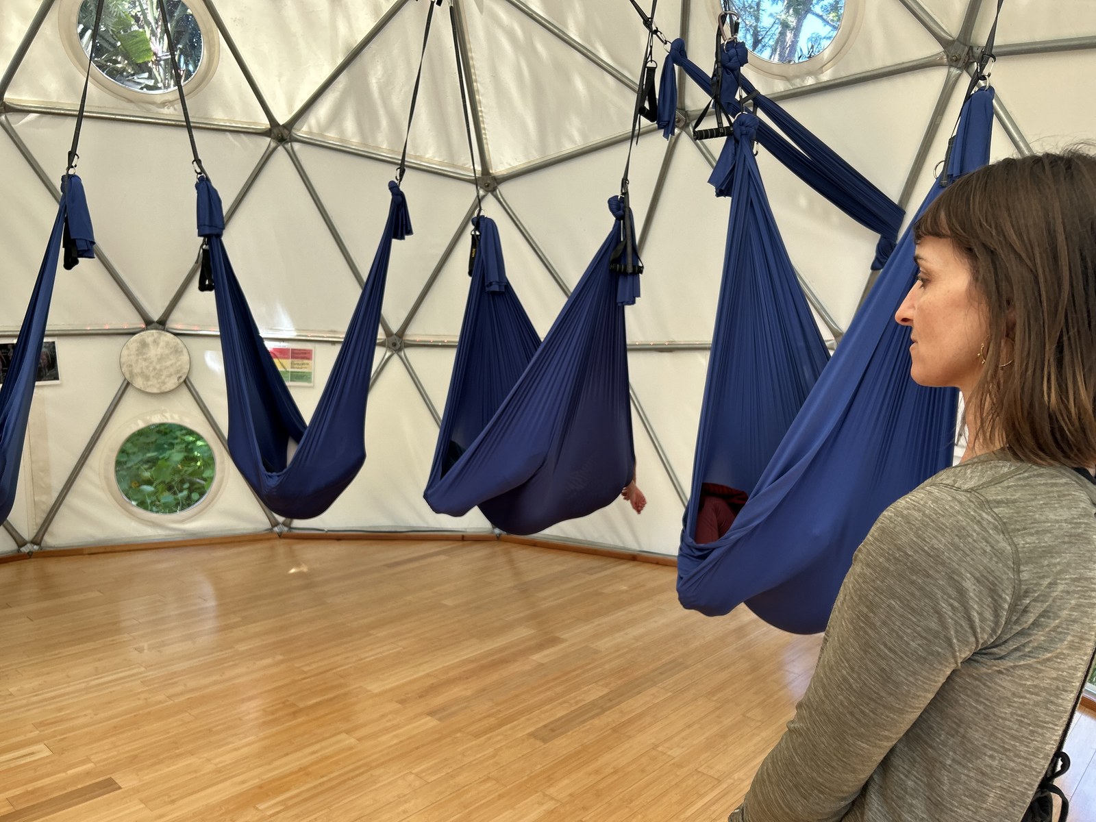 A second view across the Aum Dome floor with the swings hanging in a ring and a figure looking on from the near side