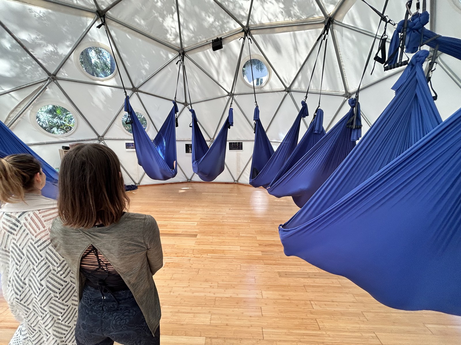 A person standing in the foreground looking across the Aum Dome at the ring of swings hanging around the room